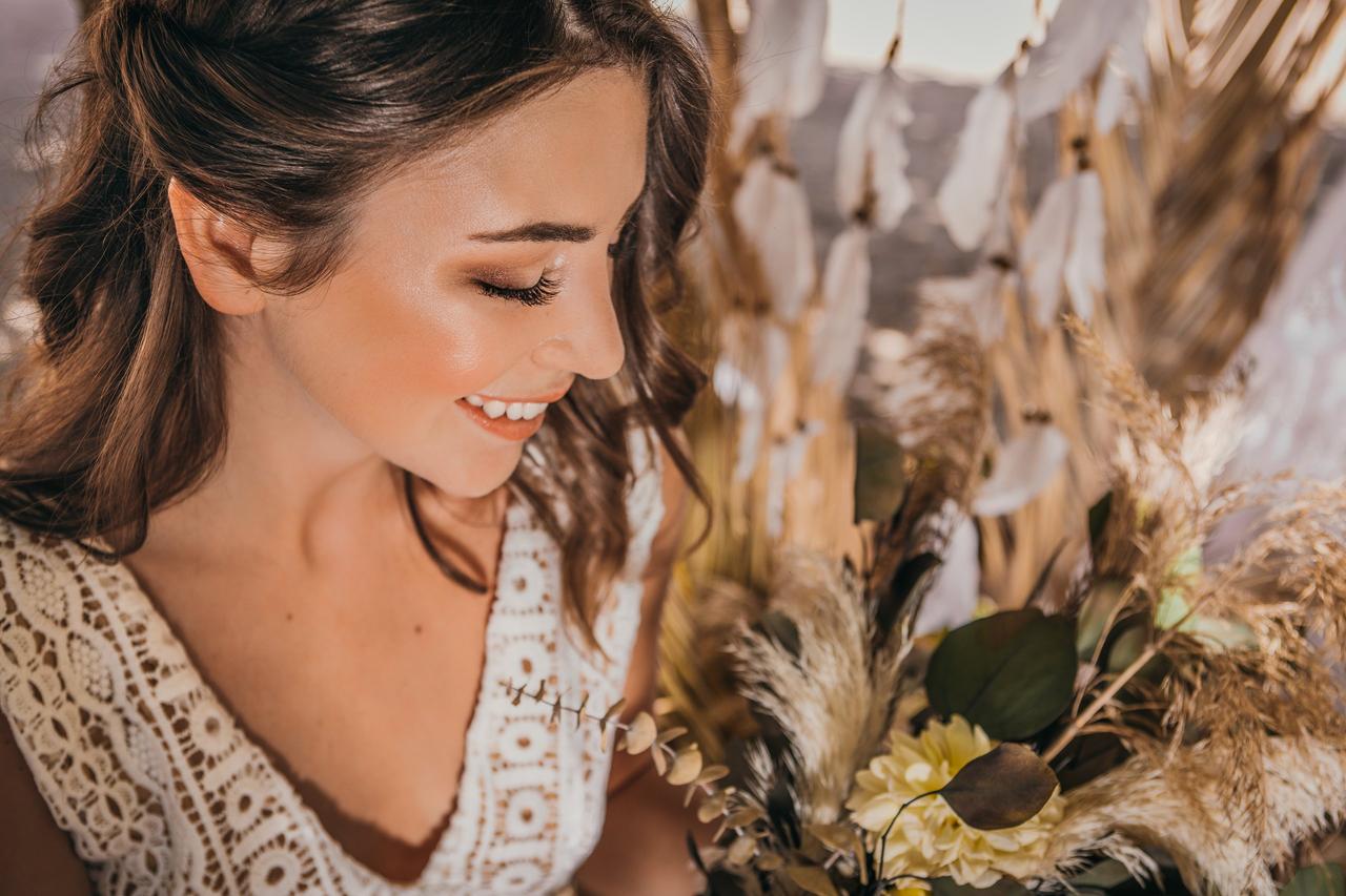 Mujer sonriente con maquillaje glow y flores de fondo