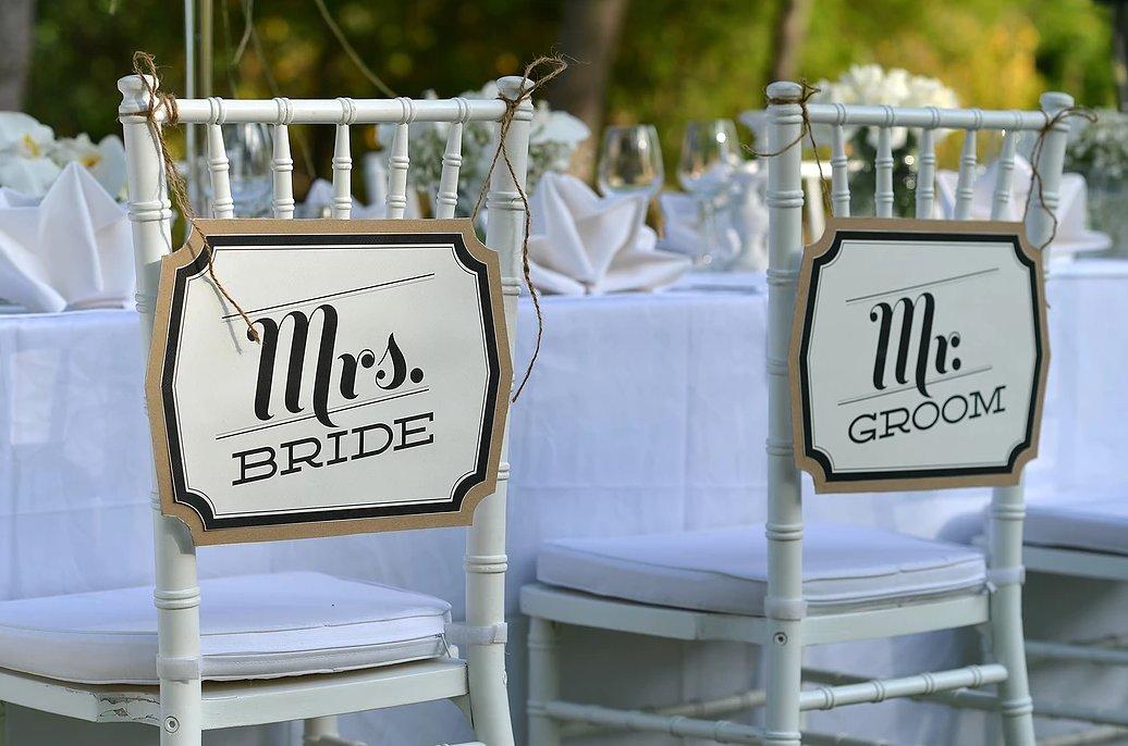 Sillas de los novios el día de la boda con carteles de Mrs. Bride y Mr. Groom