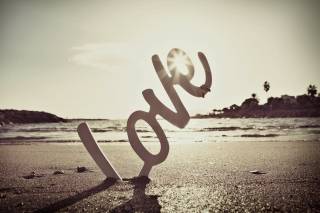 Letras formando la palabra Love sobre la arena de la playa el día de la boda