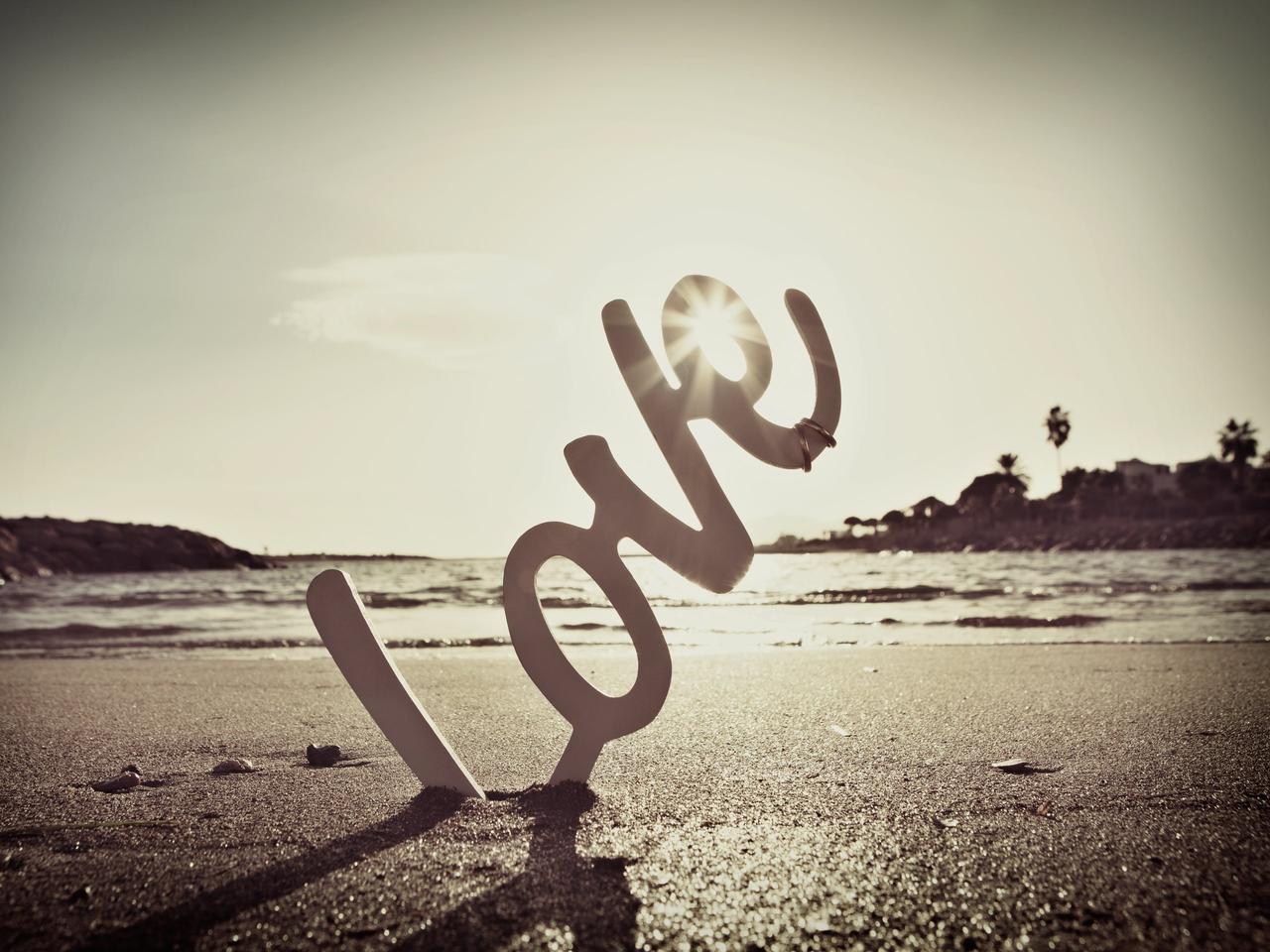 Letras formando la palabra Love sobre la arena de la playa el día de la boda