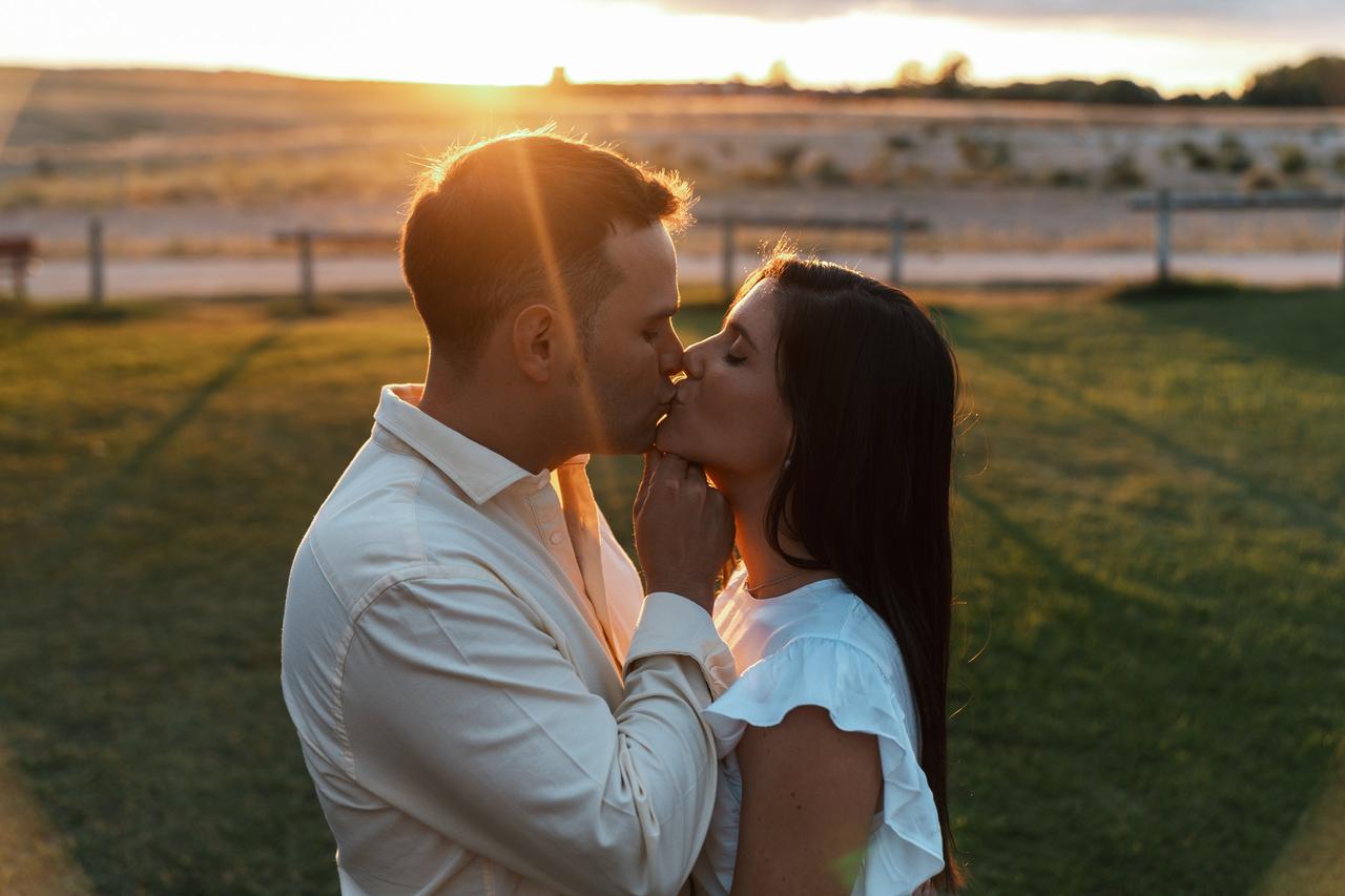 Casal de menino e menina se beijam no meio de um campo durante o pôr do sol - há algo mais íntimo que sexo