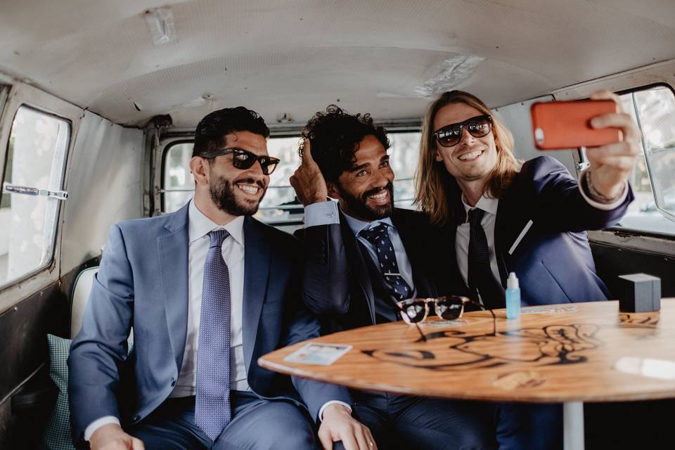 Corbata o pajarita: tres chicos con traje y sonrientes se hacen un selfie en el interior de un coche