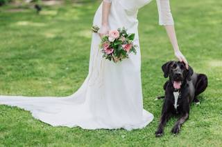 Perros bodas: novia con ramo de flores en una mano acaricia con la otra a su perro