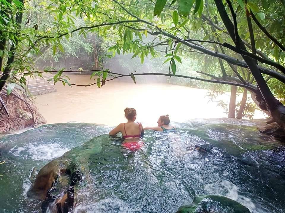 Dos chicas bañándose en una piscina natural en medio de la naturaleza