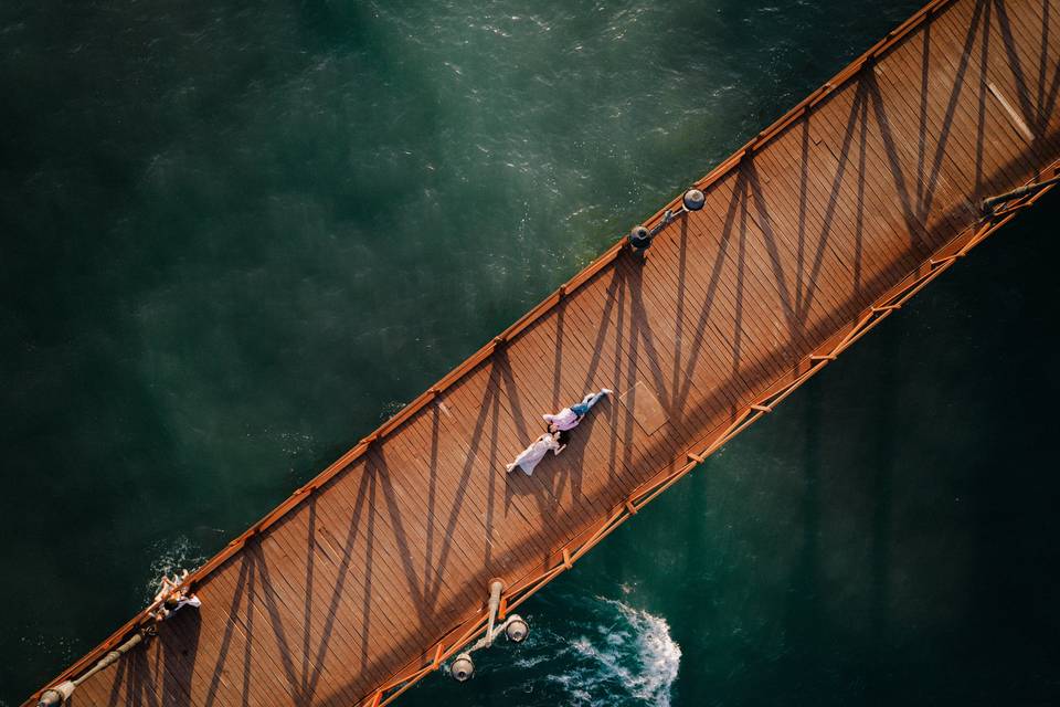 Regalo primer aniversario boda: toma aérea de una pareja estirada en el suelo de un puente