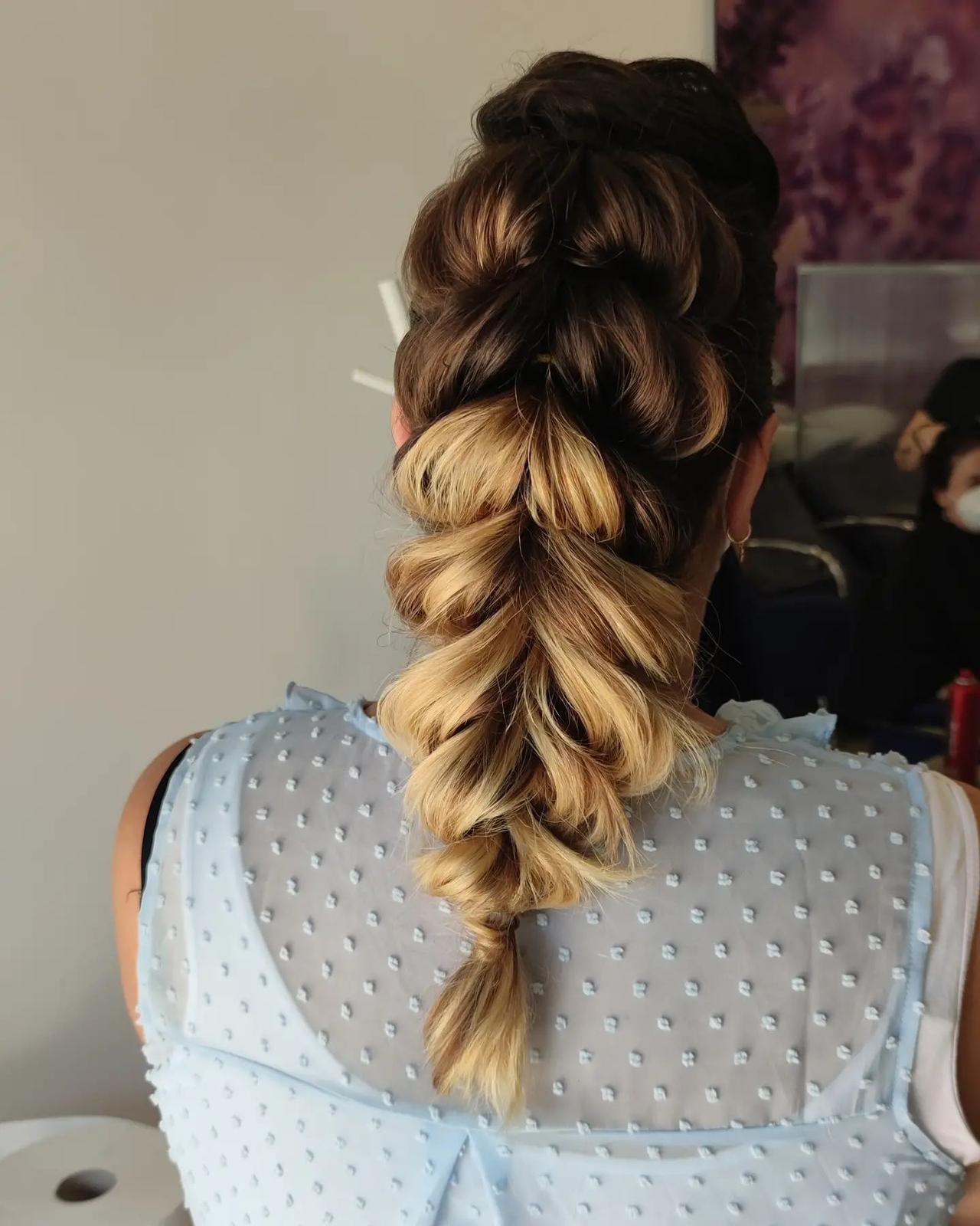 peinados trenzas boda: mujer rubia de espaldas con blusa de plumeti azul y trenza holandesa voluminosa