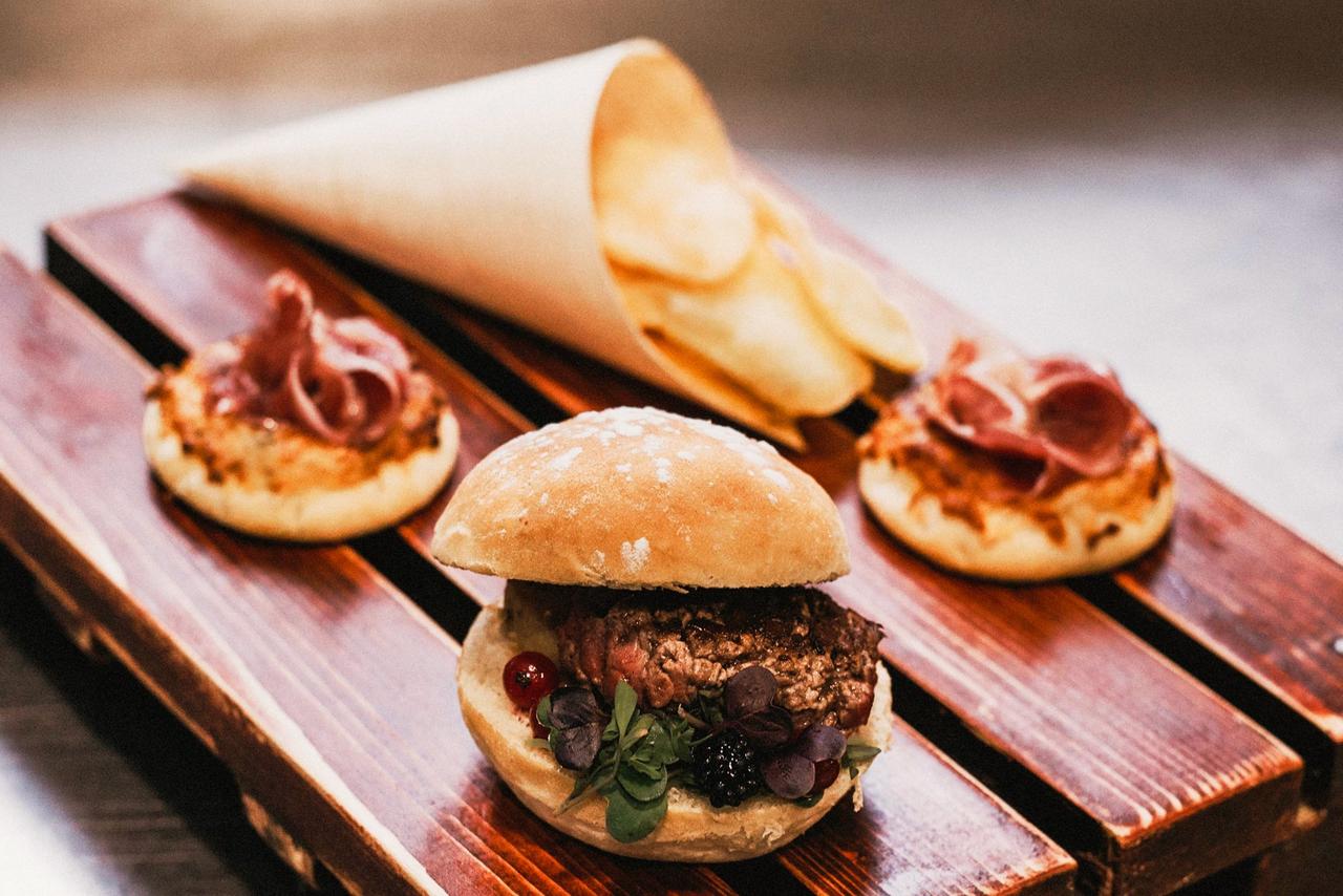 Base de madera con mini burguer, mini pizas y cono con patatas chips