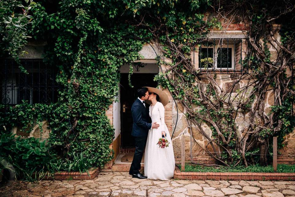 Gastos de una boda: pareja de recién casados besándose en un exterior luciendo sus respectivos outfits nupciales