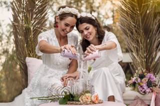 Dos chicas con dos tarros de cristal con arena de diferente color la vierten al mismo tiempo en un recipiente más grande: juntándola para siempre. Un ritual simbólico muy habitual en las bodas civiles que se conoce como la ceremonia de la arena