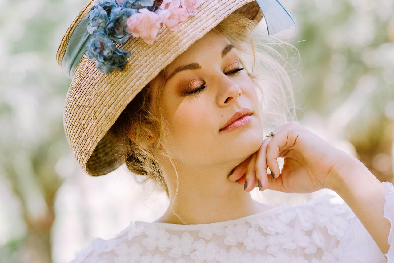 Chica con los ojos cerrados maquillada de forma sencilla con sombrero en la cabeza