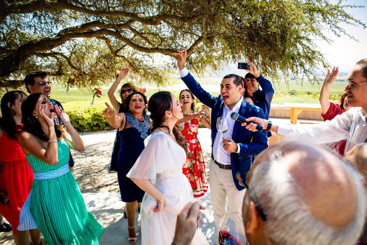 Muchas personas elegantemente vestidas se lo pasan de lo lindo cantando en un exterior al aire libre 