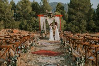 Decoración boda exterior: dos chicas vestidas de novia se cogen las manos junto al altar de su boda civil al aire libre