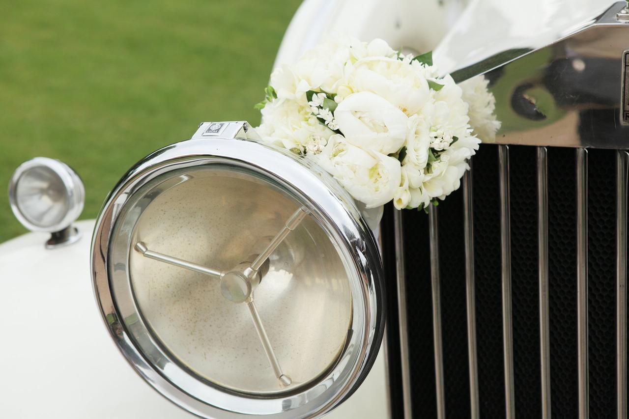 Faro delantero de un coche clásico decorado con un ramo de flores blancas