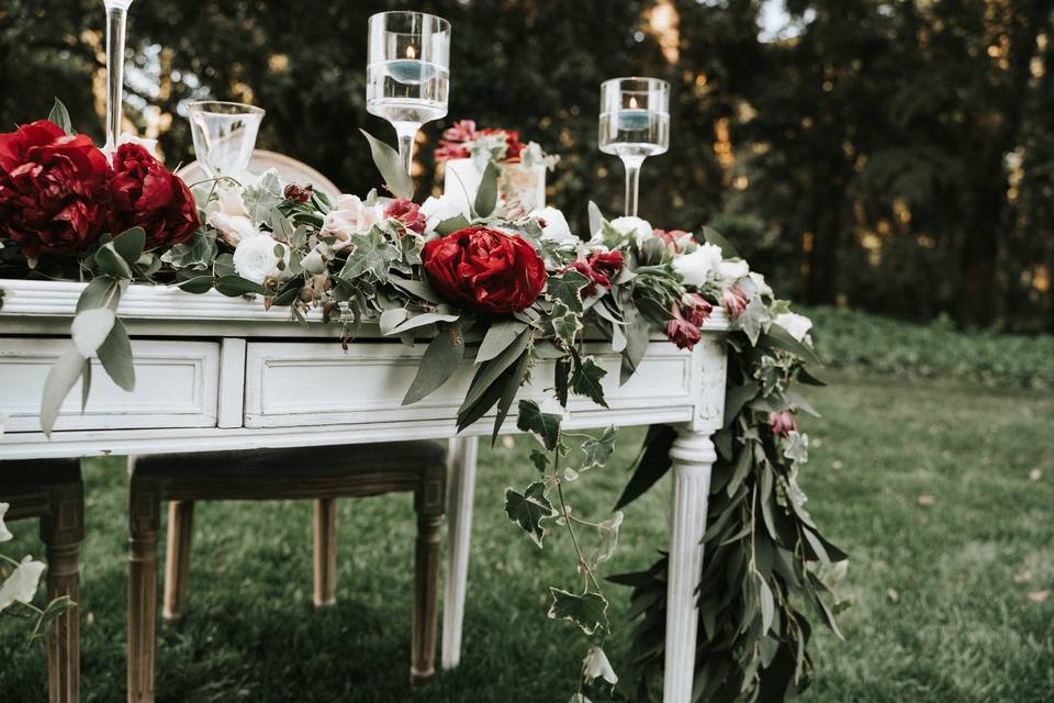 mueble antiguo con candelabros y flores rojas y blancas perfecto para la decoración de la boda