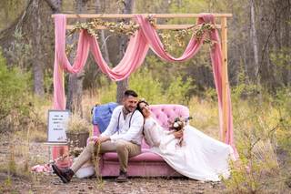 Pareja de recién casados posa en su photocall de boda con sofá y telas rosas