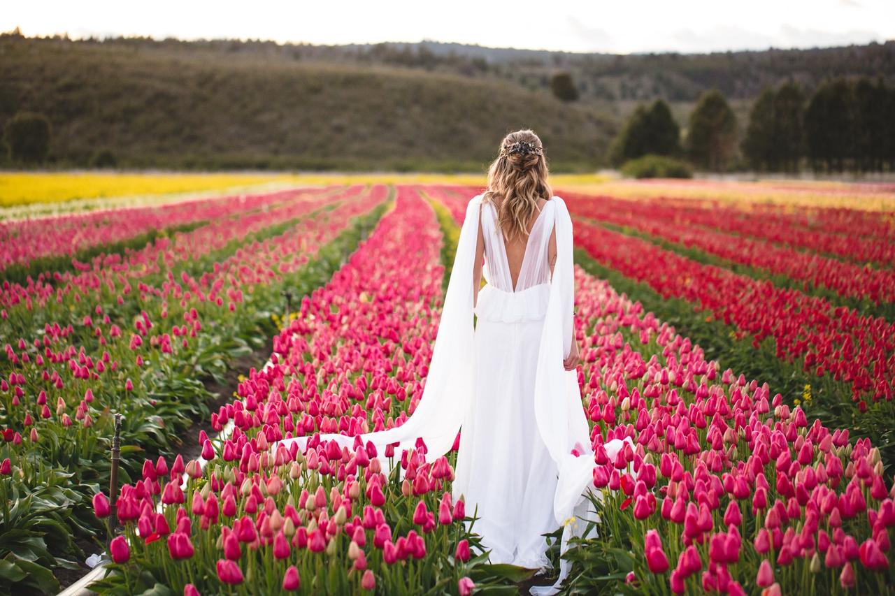 Flores para boda: novia de espaldas en un gran campo de tulipanes de color fucsia