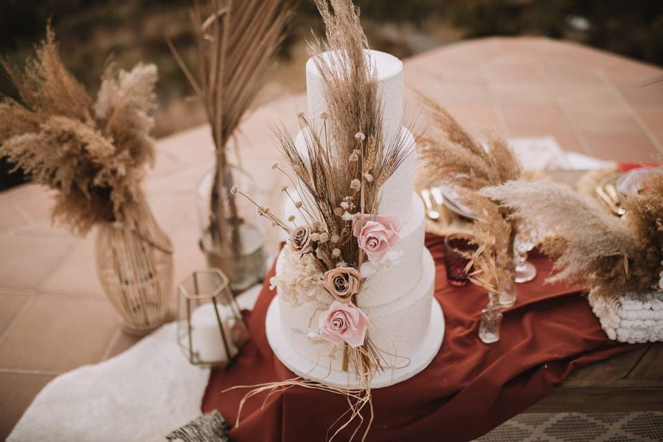 Tarta de boda en fondant blanco, decorada con rosas de diferentes colores, espigas y hierba de la pampa