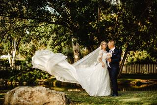 Pareja de hombre y mujer vestidos de boda con la cola de ella al vuelo en un fondo verde de bosque