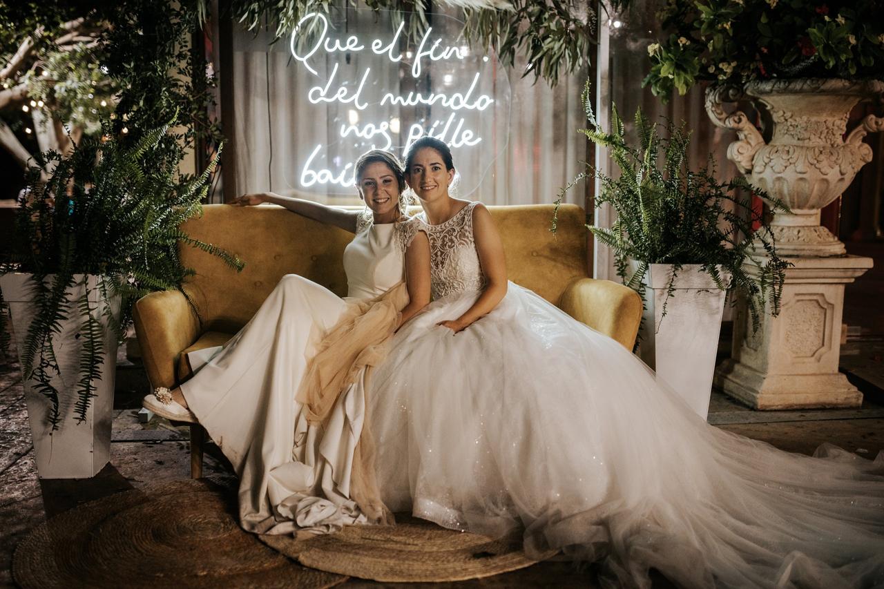 Dos novias sentadas en un sofá de su photocall para boda