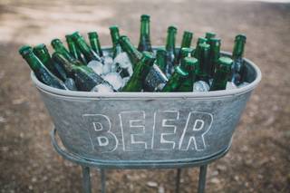 Rincón cerveza boda con cubo de cinc de forma ovalada y lleno de cervezas y hielos sobre una estructura metálica