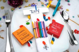 Regalos de boda para niños: lápices de colores, piruletas, confeti y caramelos de colores en una mesa