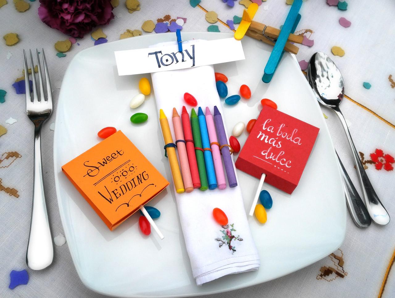 Regalos de boda para niños: lápices de colores, piruletas, confeti y caramelos de colores en una mesa