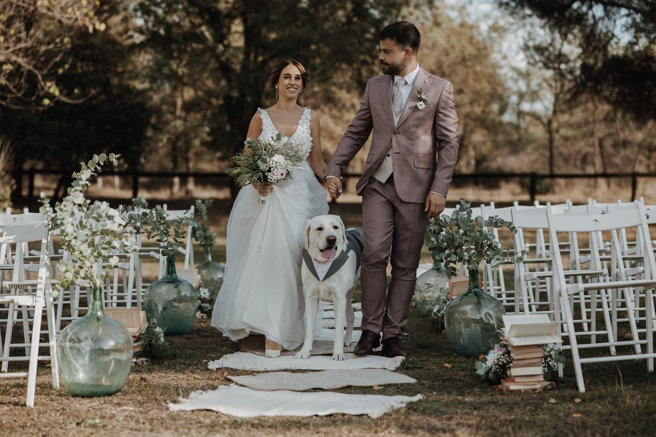 Perros boda: pareja de recién casados parada en medio del pasillo de su ceremonia de boda al aire libre