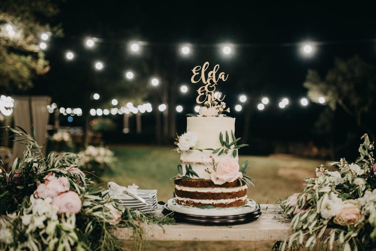 Tarta de boda de varios pisos con un cake topper con los nombres de la pareja