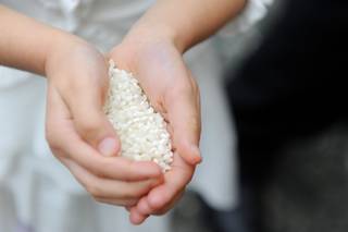 Por qué se tira arroz en las bodas: manos infantiles sujetan un buen puñado de arroz blanco