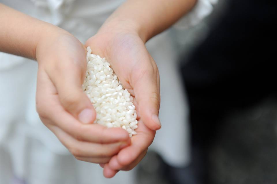 Manos infantiles sujetando un buen puñado de arroz blanco