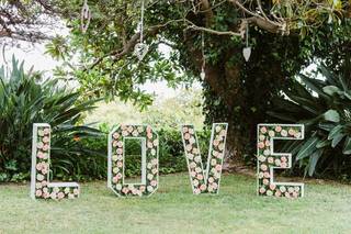 Letras grandes formando la palabra Love el día de la boda y llenas de flores frescas y elementos vegetales