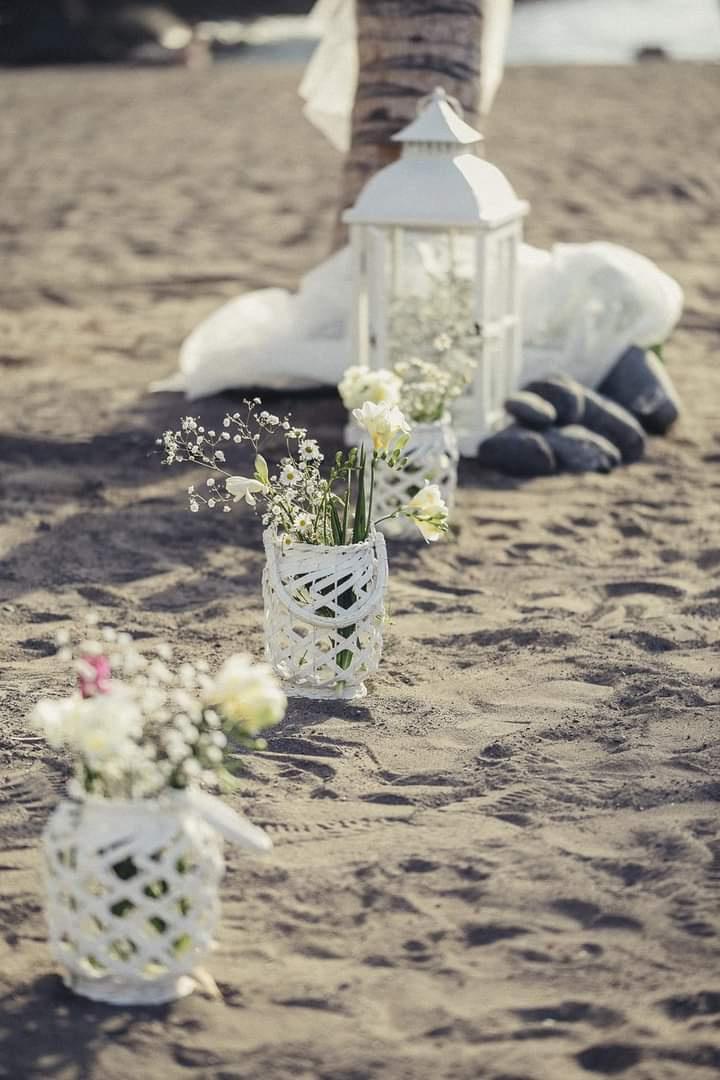 Boda ibicenca decoración con jarroncitos blancos con flores y farolillos del mismo color