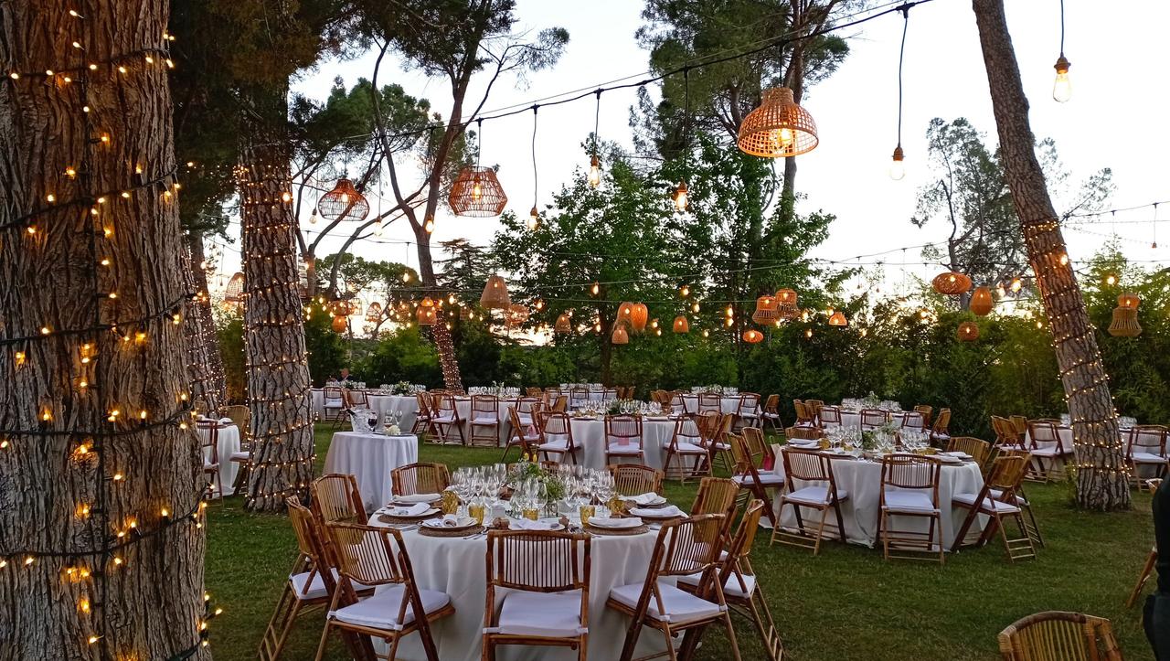 Bonito jardín con mesas redondas preparadas para un banquete de boda al aire libre en Edificación imponente del Castillo de Viñuelas, de Madrid