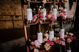 Seating plan original de boda con botellas de vino y muchas flores