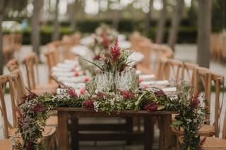 Decoración boda exterior: larga mesa de madera con mucho follaje en uno de sus extremos