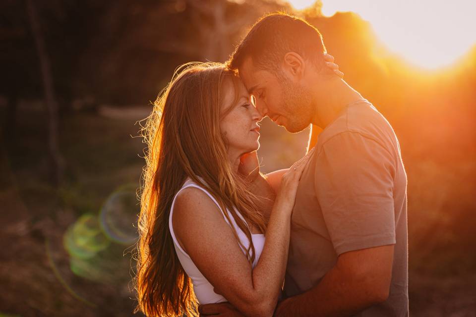 Relación lat: chico y chica con ropa casual y muy acaramelados durante una puesta de sol