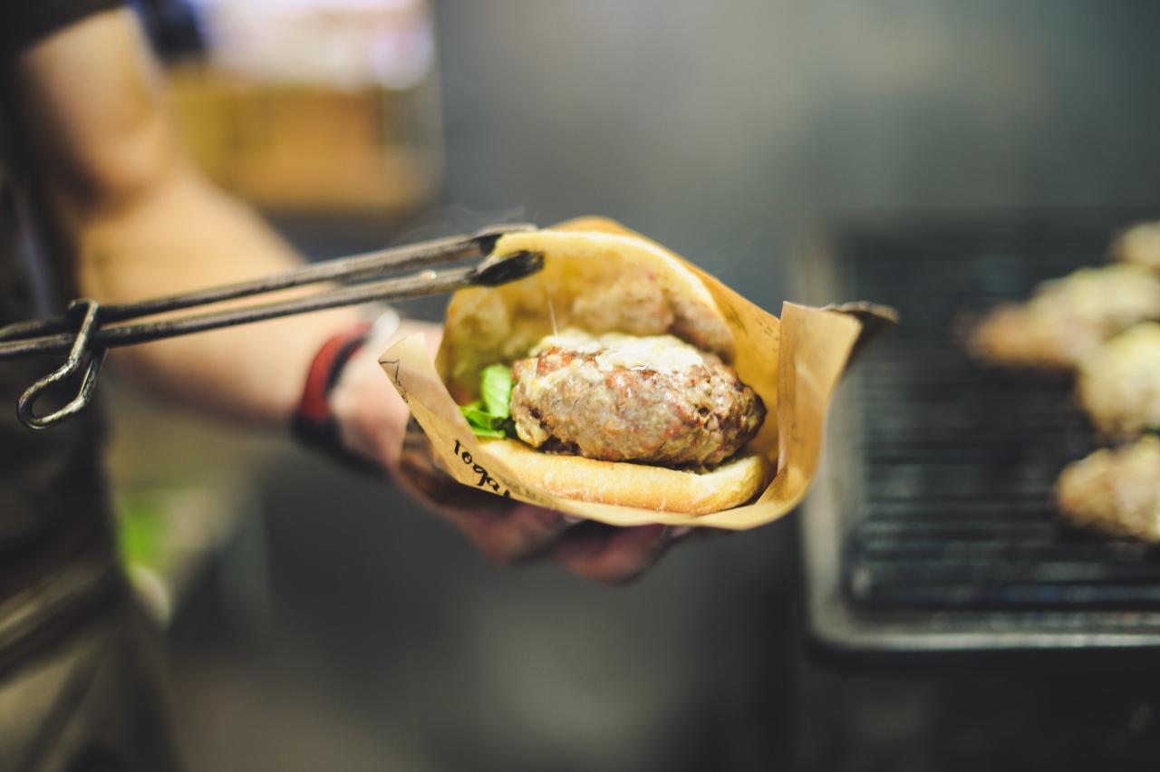 hamburguesa dentro de pan en las manos de una persona