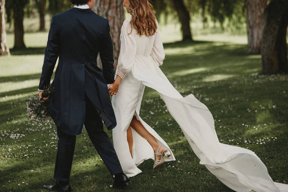 Cómo usar tacón sin que duelan pies: novia de espaldas con un vestido con abertura trasera que deja a la vista sus zapatos de novia