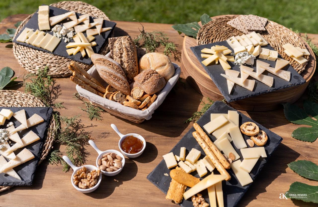 Mesa de quesos boda: mesa de madera con bases de pizarra con distintos tipos de quesos