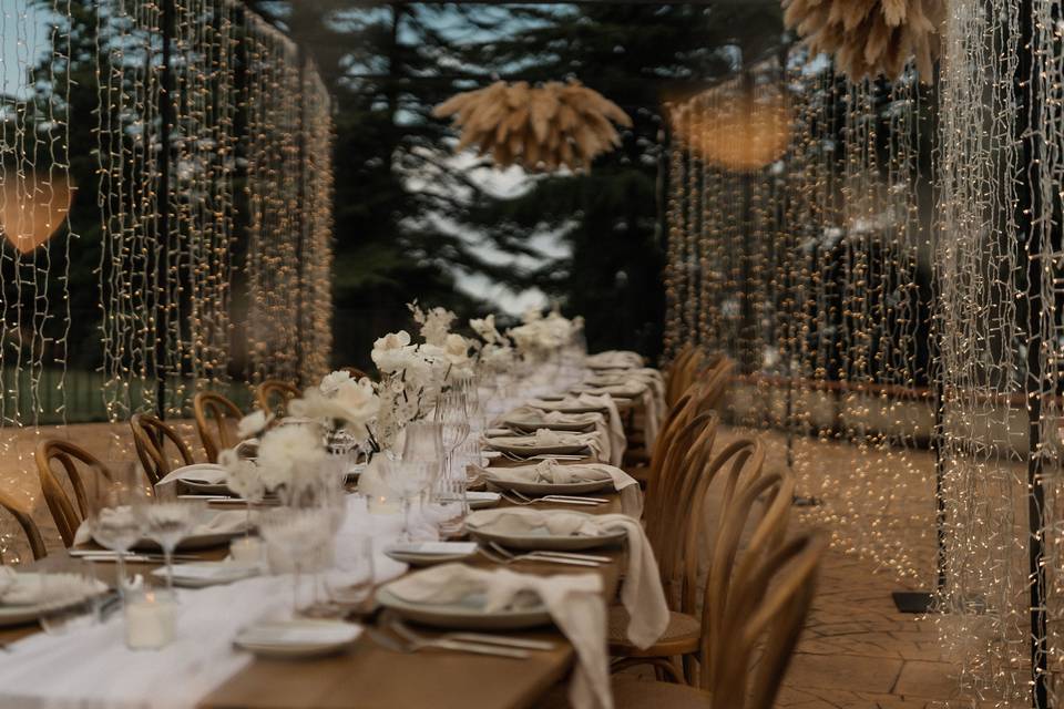 Larga mesa rectangular de madera muy bien vestida para una comida o cena especial y envuelta en tiras de luces led