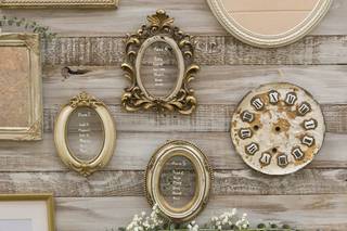 Decoración vintage para el photocall de boda con un reloj de época y varios marcos antiguos sobre una base de madera