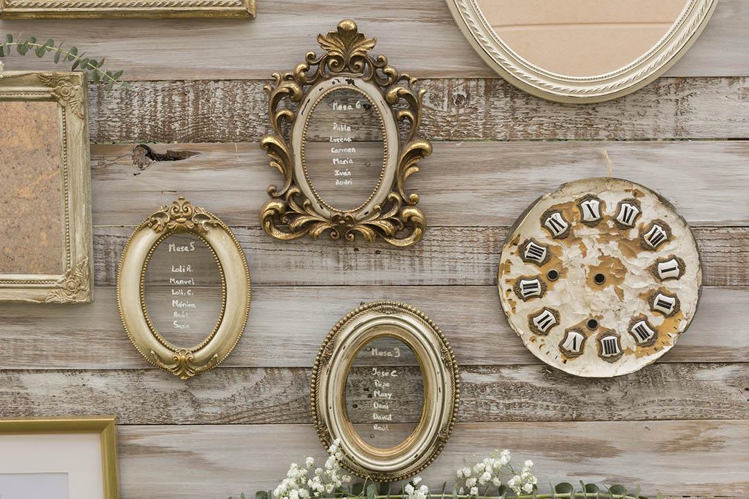 Decoración vintage para el photocall de boda con un reloj de época y varios marcos antiguos sobre una base de madera