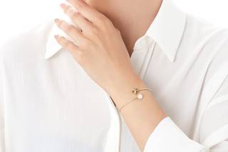 Chica con una camisa blanca con una pulsera rígida abierta con una estrella y una perla