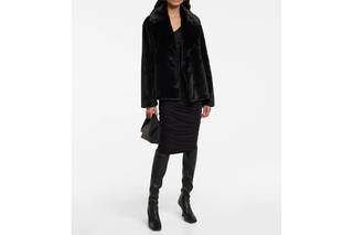 Chica con un abrigo de piel sintética negro y bolso de mano del mismo color