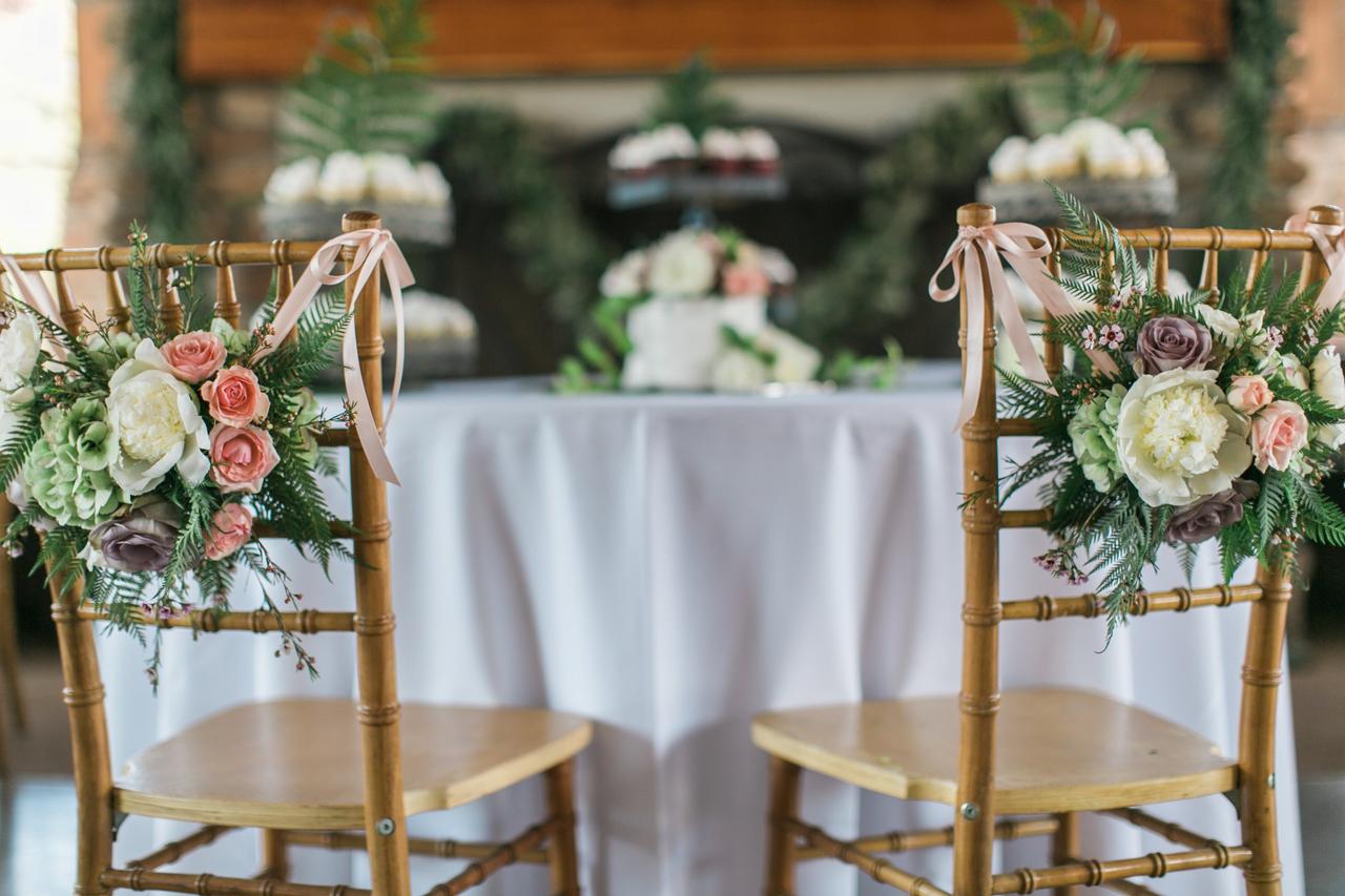 Sillas de los novios el día de la boda con bonitas composiciones florales en los respaldos