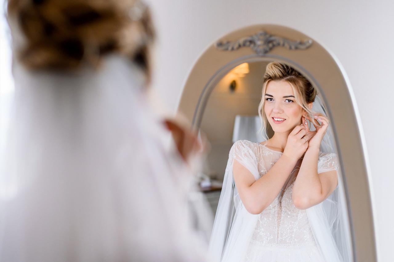 Chica rubia mirándose al espejo con un vestido de novia