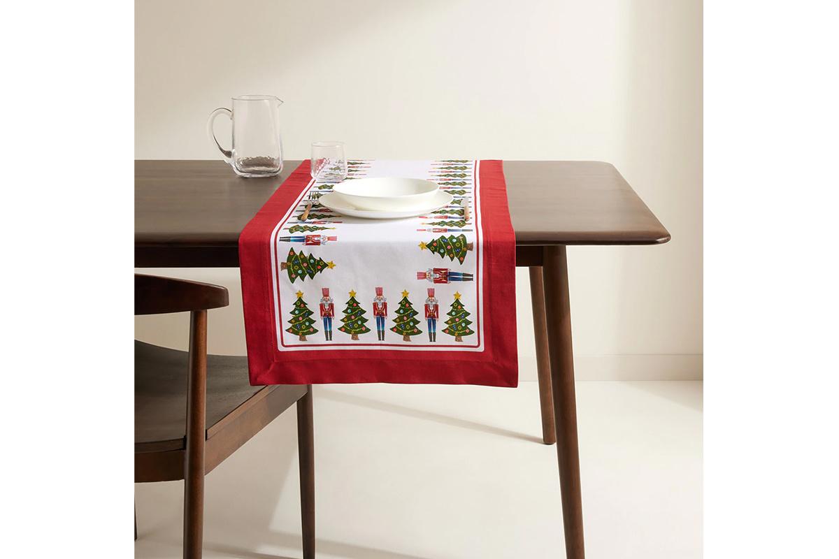 Camino de mesa con distintos motivos navideños con un ribete en rojo