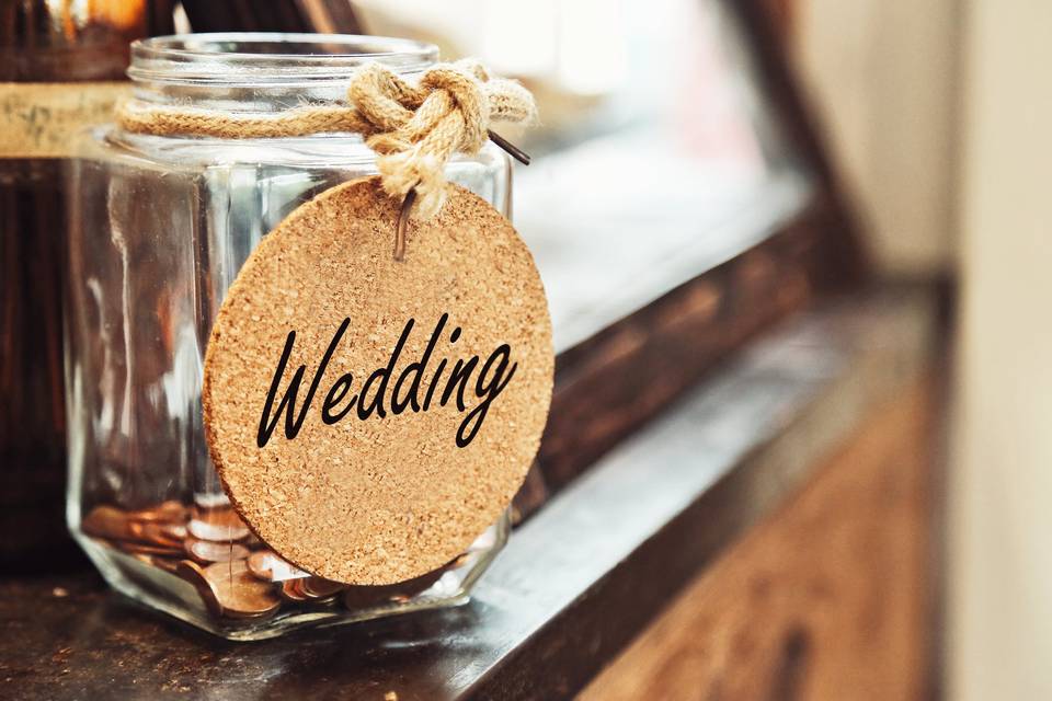 Tarro de cristal con monedas y un cartel donde pone wedding