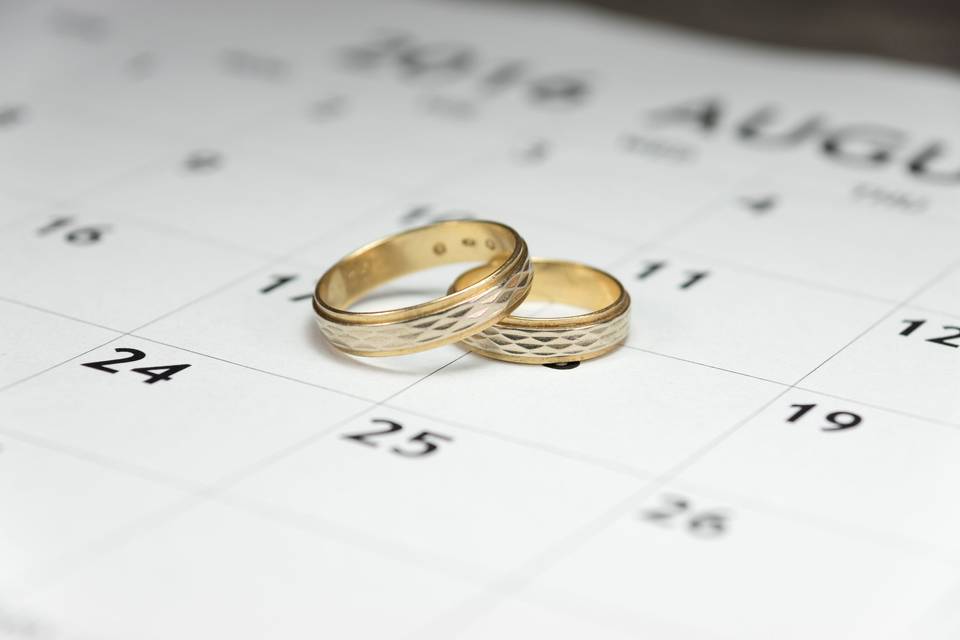 Casarse civil rápido: alianzas de boda en oro amarillo encima de un calendario