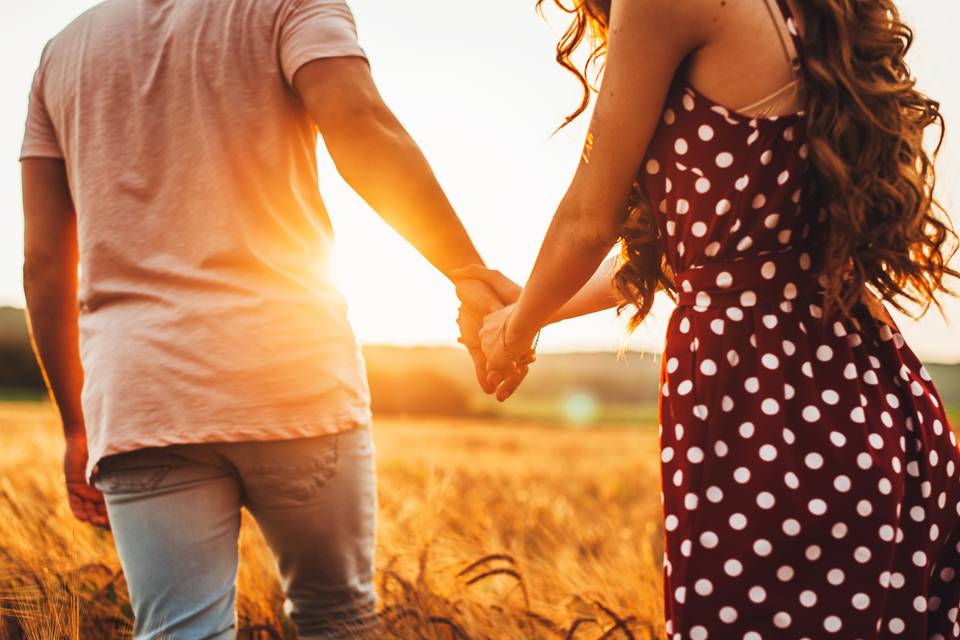 Segundas oportunidades: chico y chica cogidos de la mano en un campo durante una puesta de sol